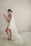 A model wearing a two tier wedding veil with large pearls by Madame Tulle