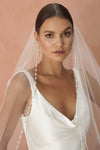 A model wearing a beaded pearl edge one tier wedding veil