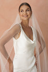 A model wearing a beaded pearl edge one tier wedding veil