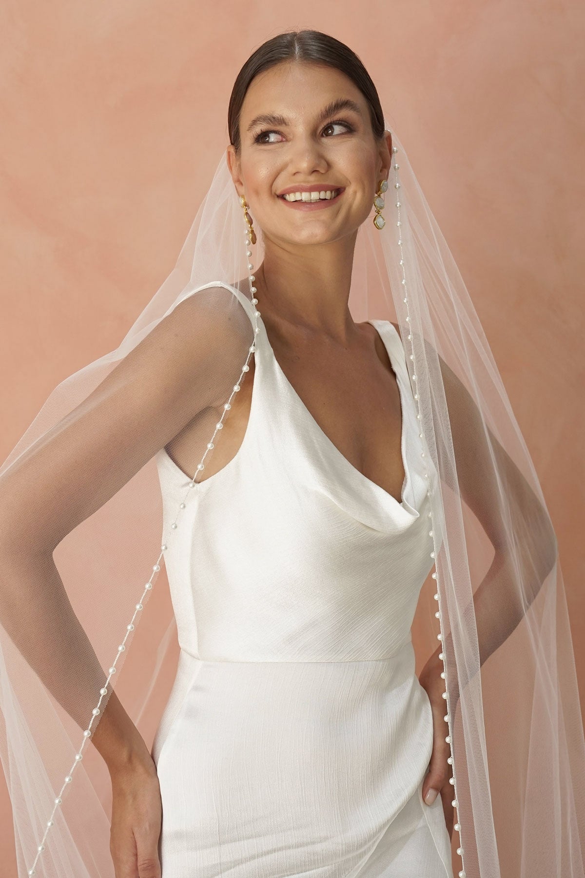 A model wearing a beaded pearl edge one tier wedding veil