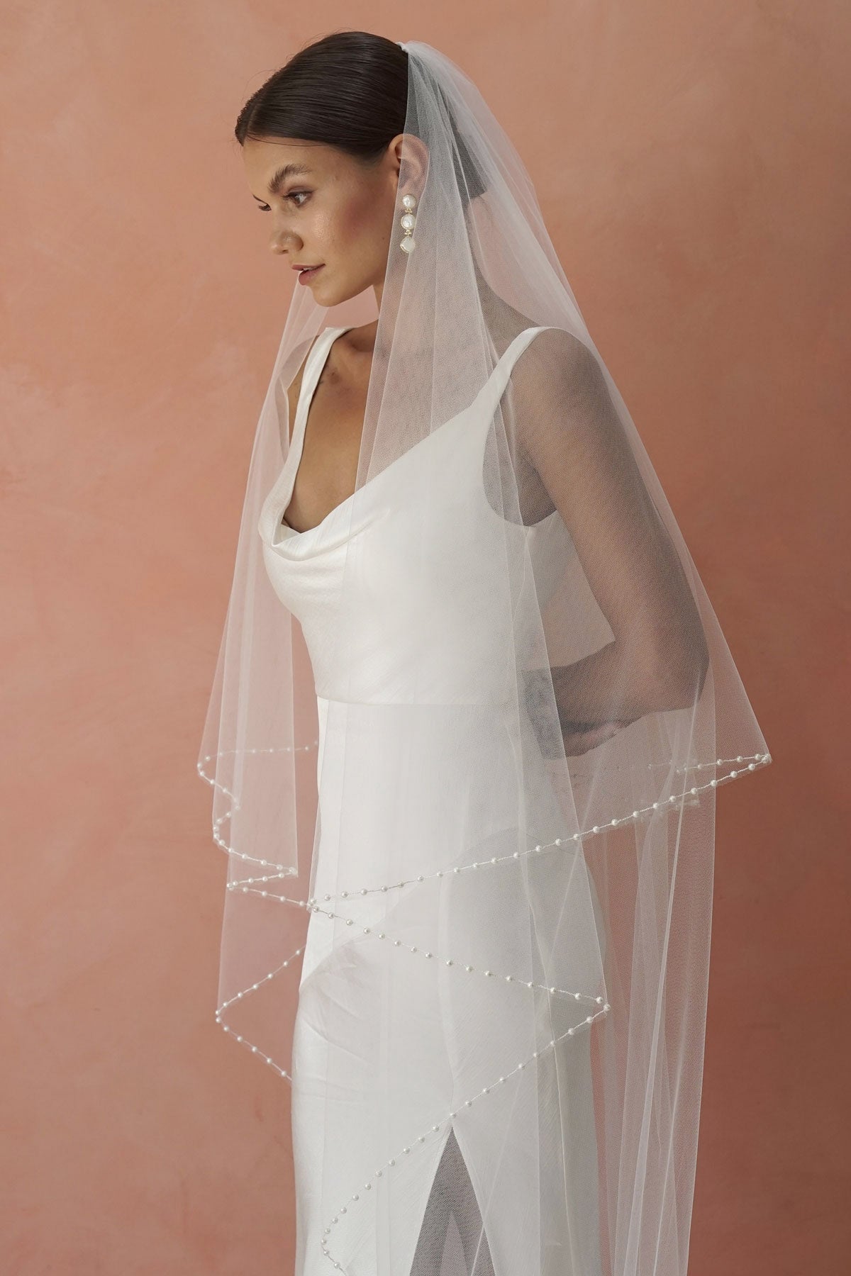 A model wearing a beaded pearl edge two tier wedding veil