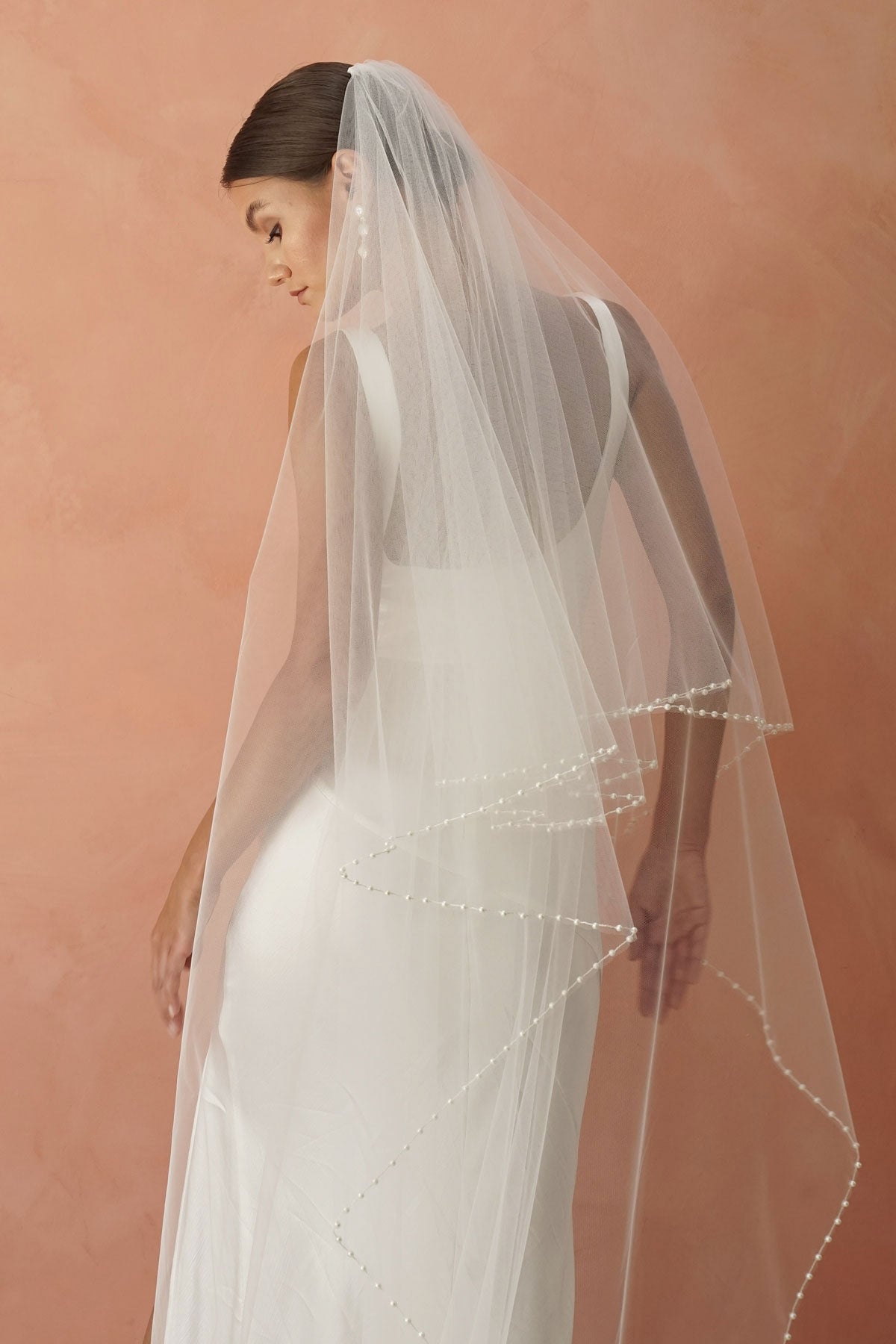 A model wearing a beaded pearl edge two tier wedding veil