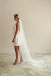 A model wearing the ELLA I minimalist one tier wedding veil in chapel length ivory colour