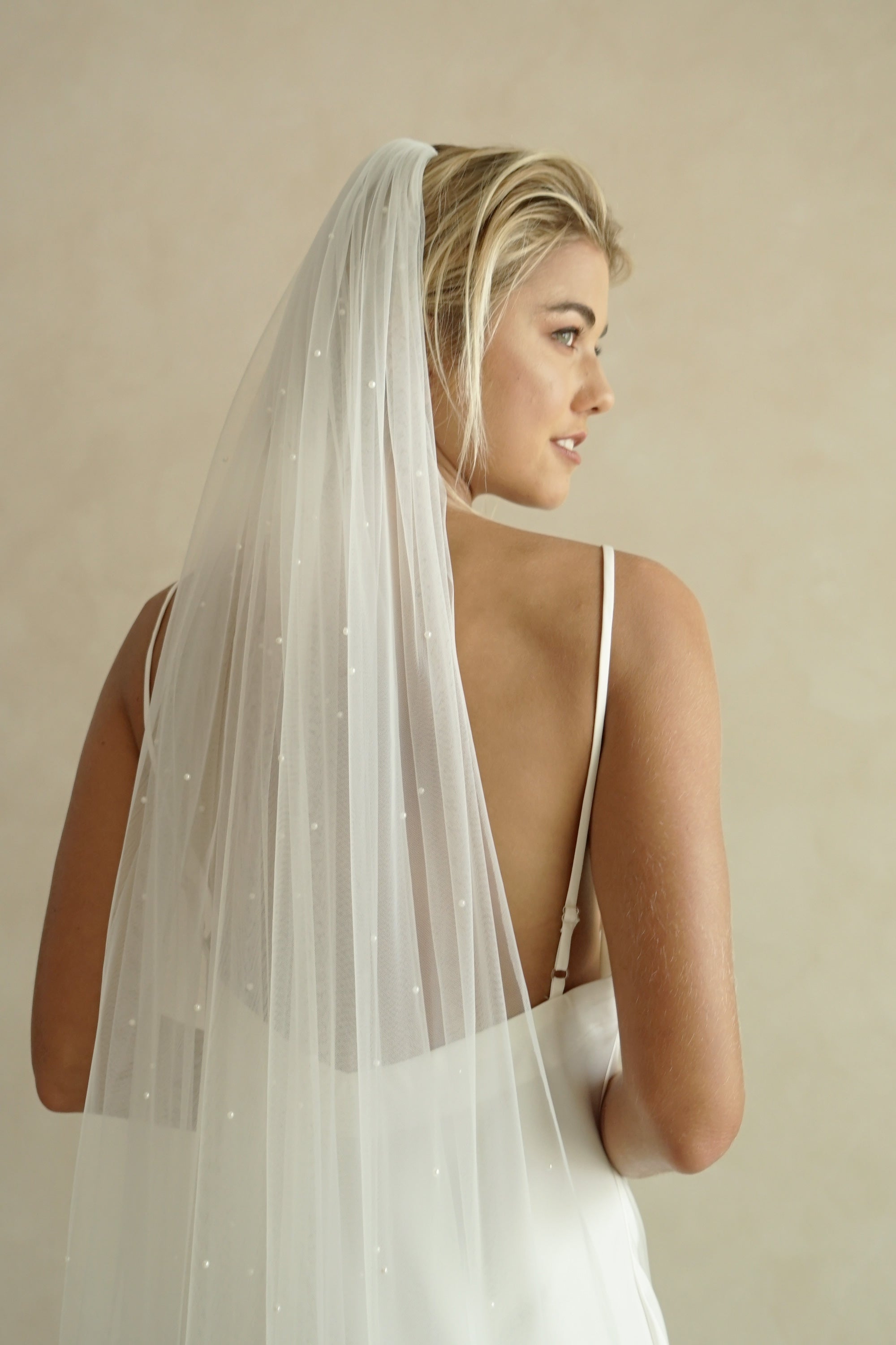 A model wearing the CHLOE one tier wedding veil with small pearls