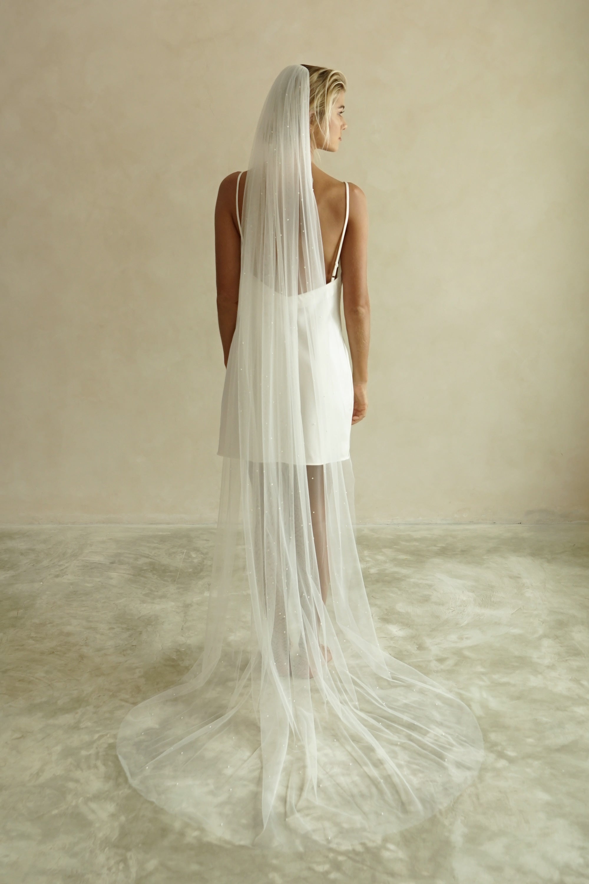 A model wearing the CHLOE one tier wedding veil with small pearls