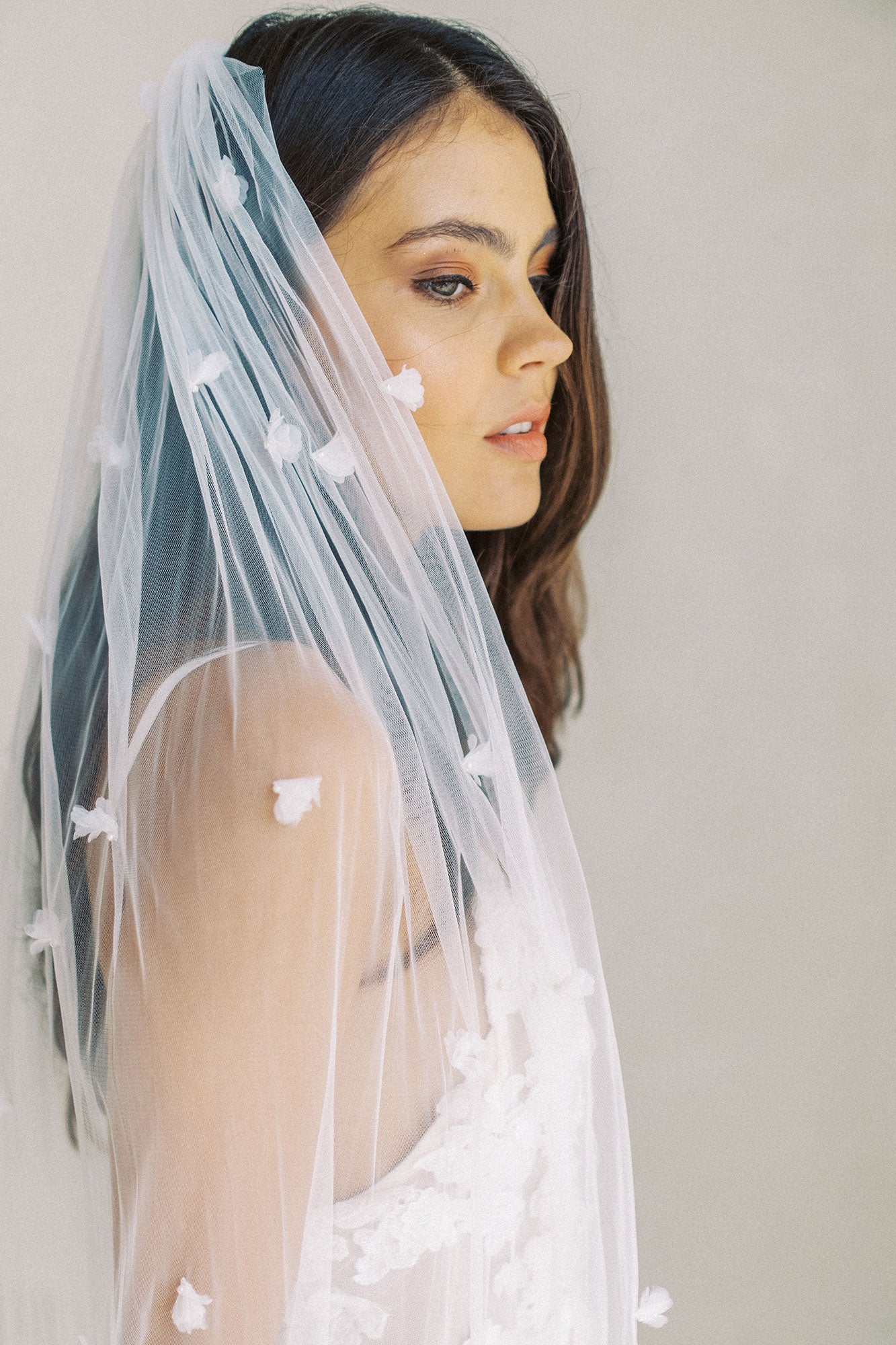 model wears wedding veil with small flowers and tiny pearls, single-tier floral veil