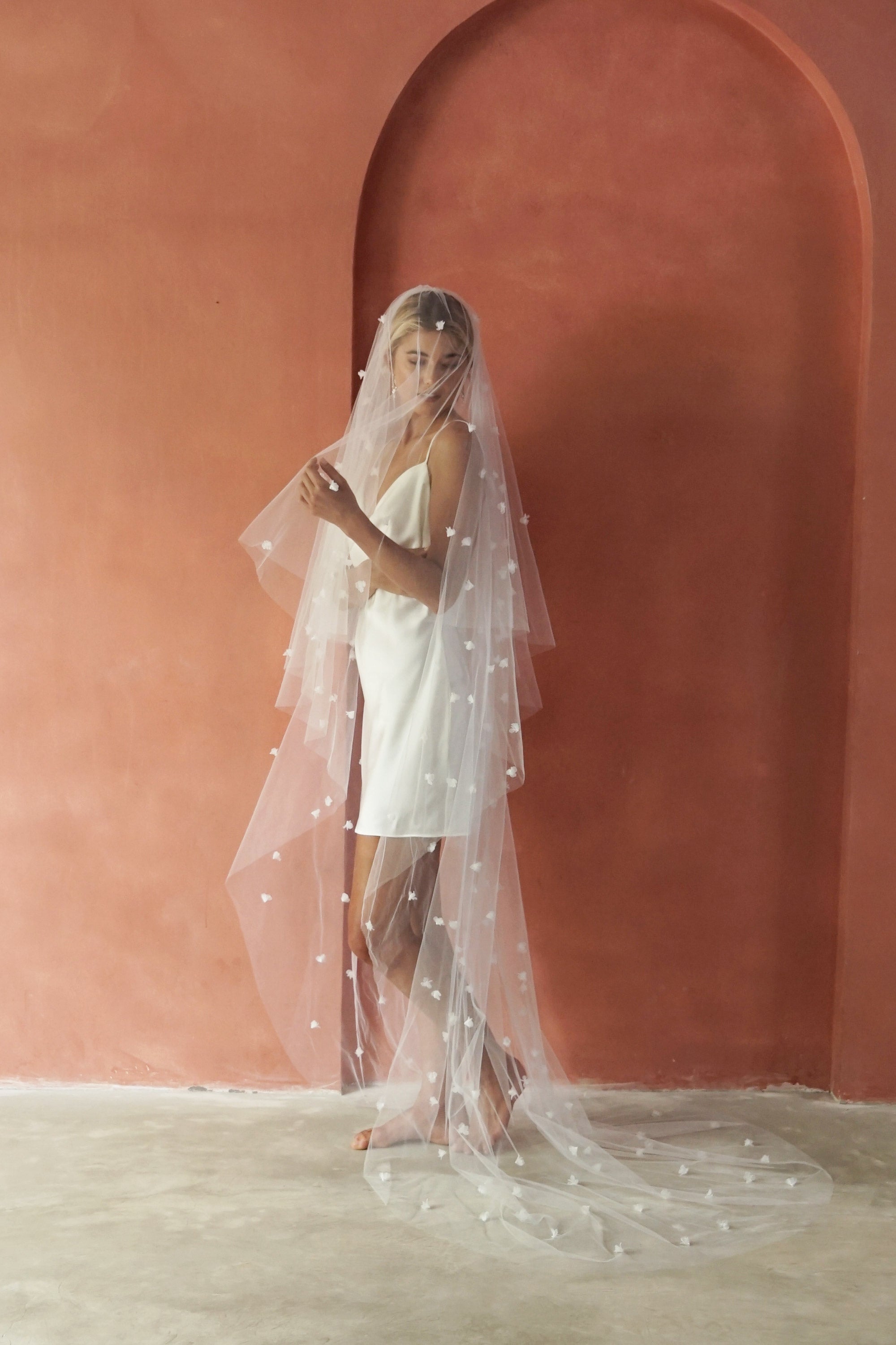 model wears wedding veil with small flowers and tiny pearls, floral drop veil