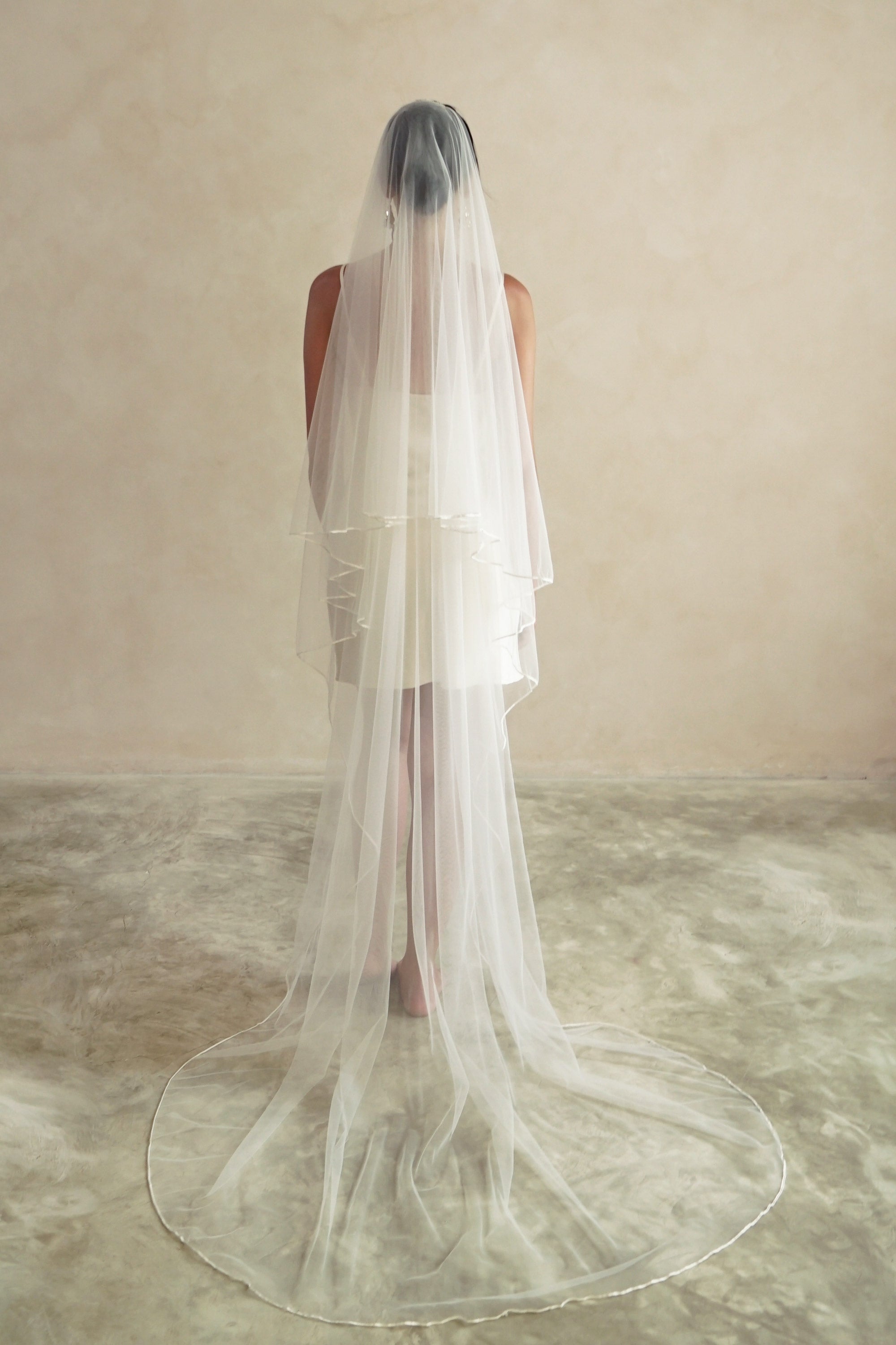 A model wearing a two tier satin cord edge wedding veil