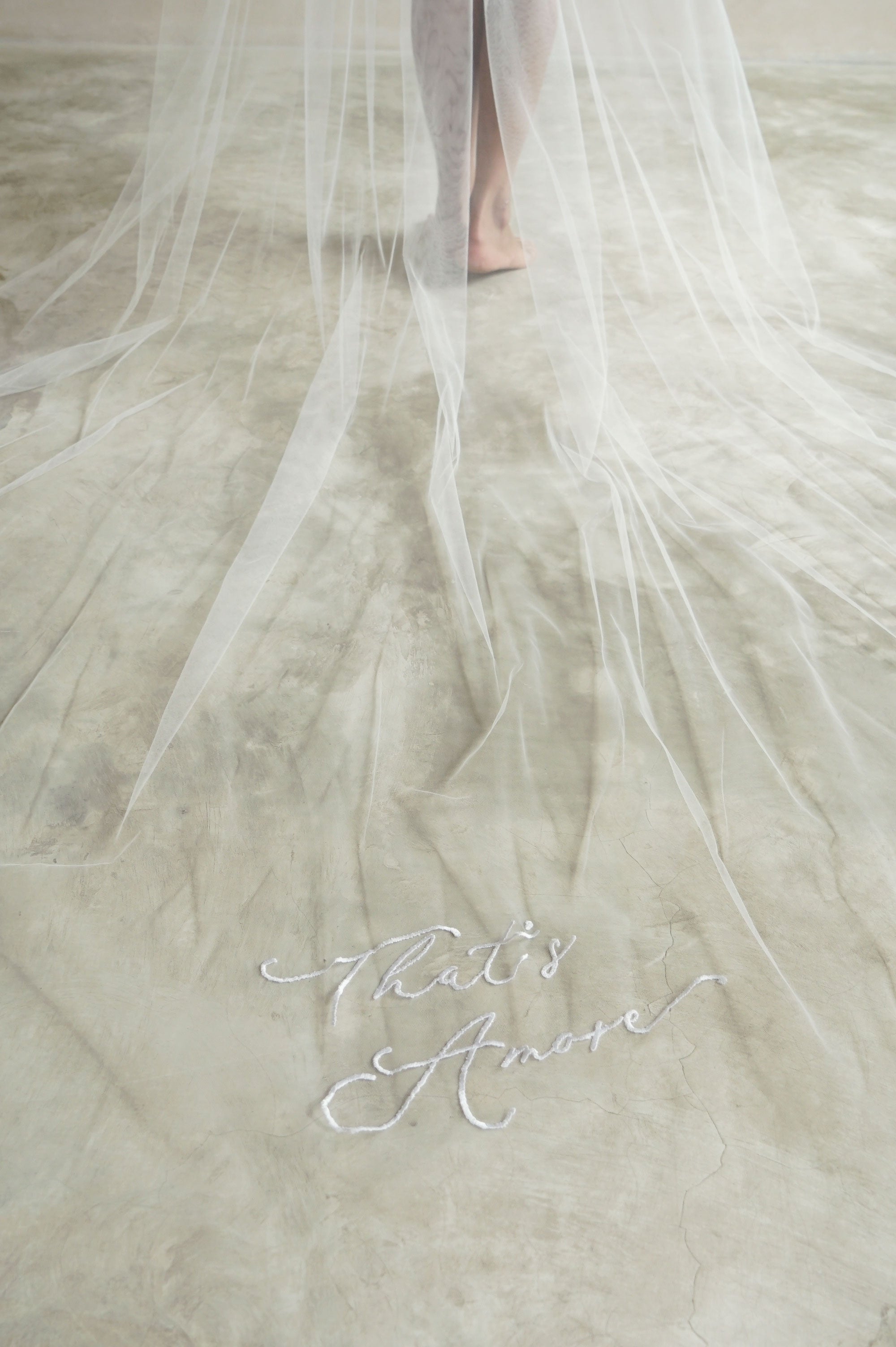 A model wearing a veil with embroidery text that's amore