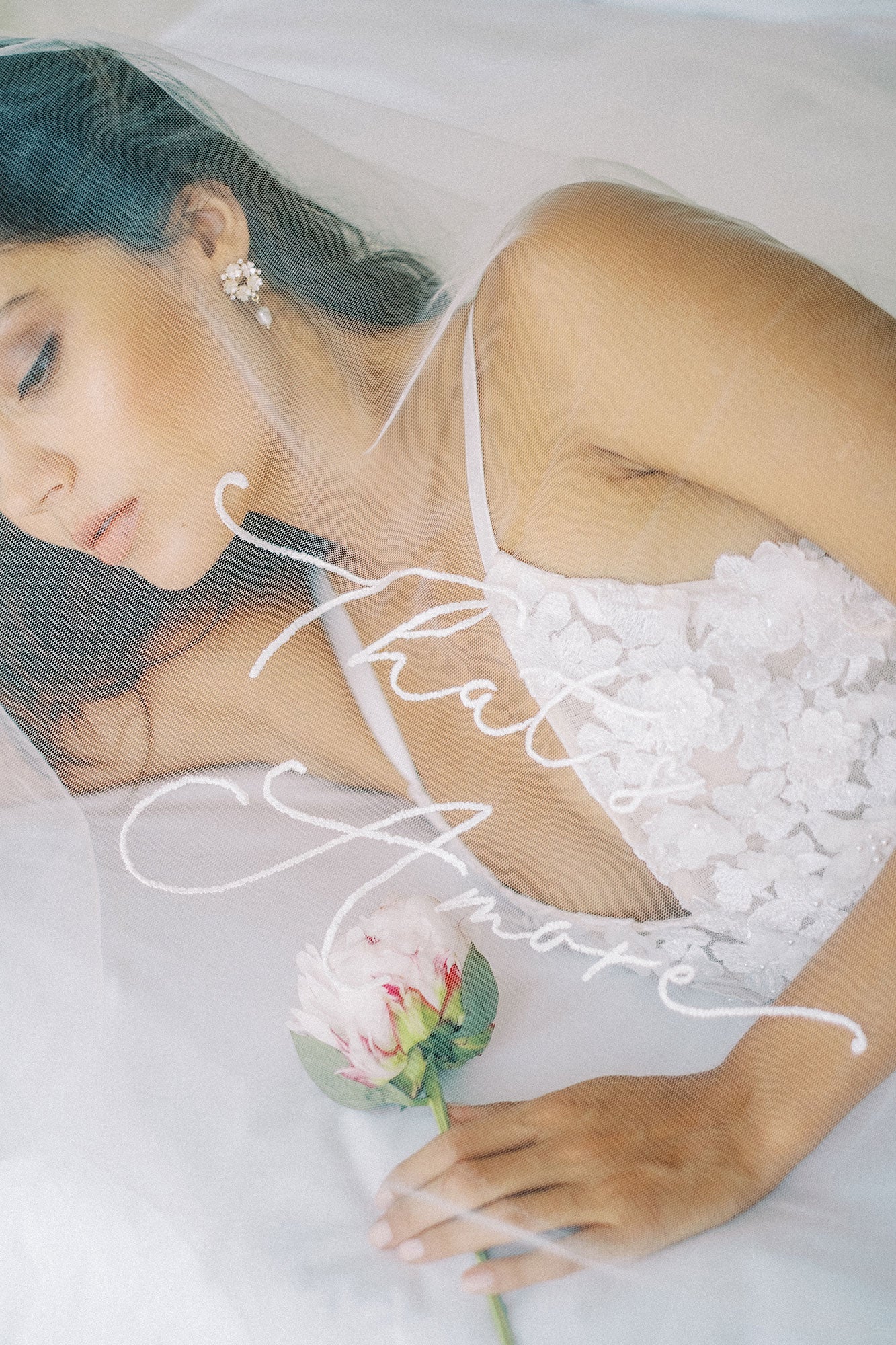 A model wearing a veil with embroidery text that's amore