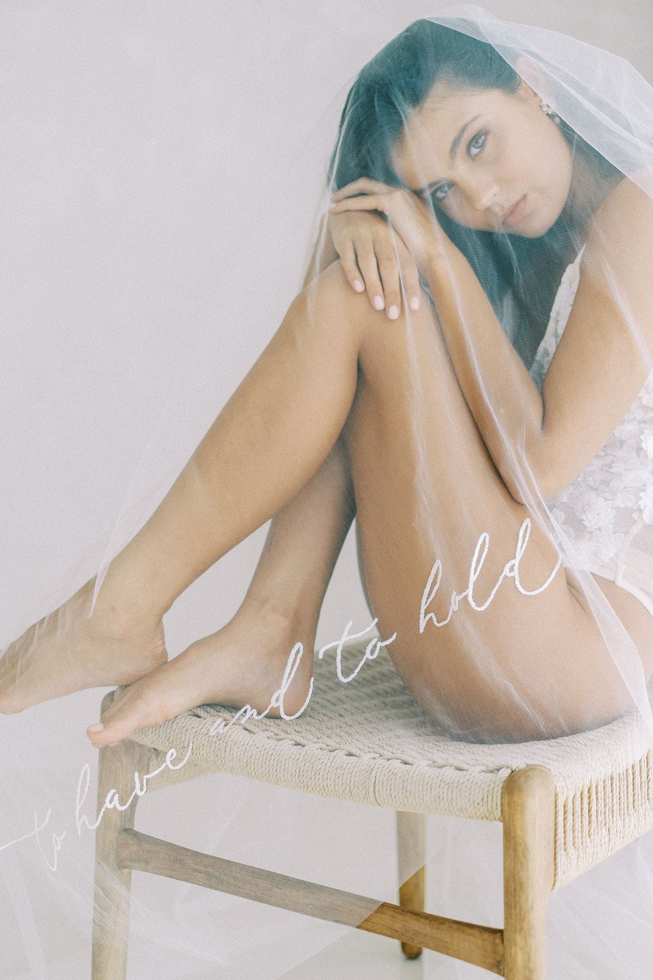 A model wearing a wedding veil with embroidery text to have and to hold