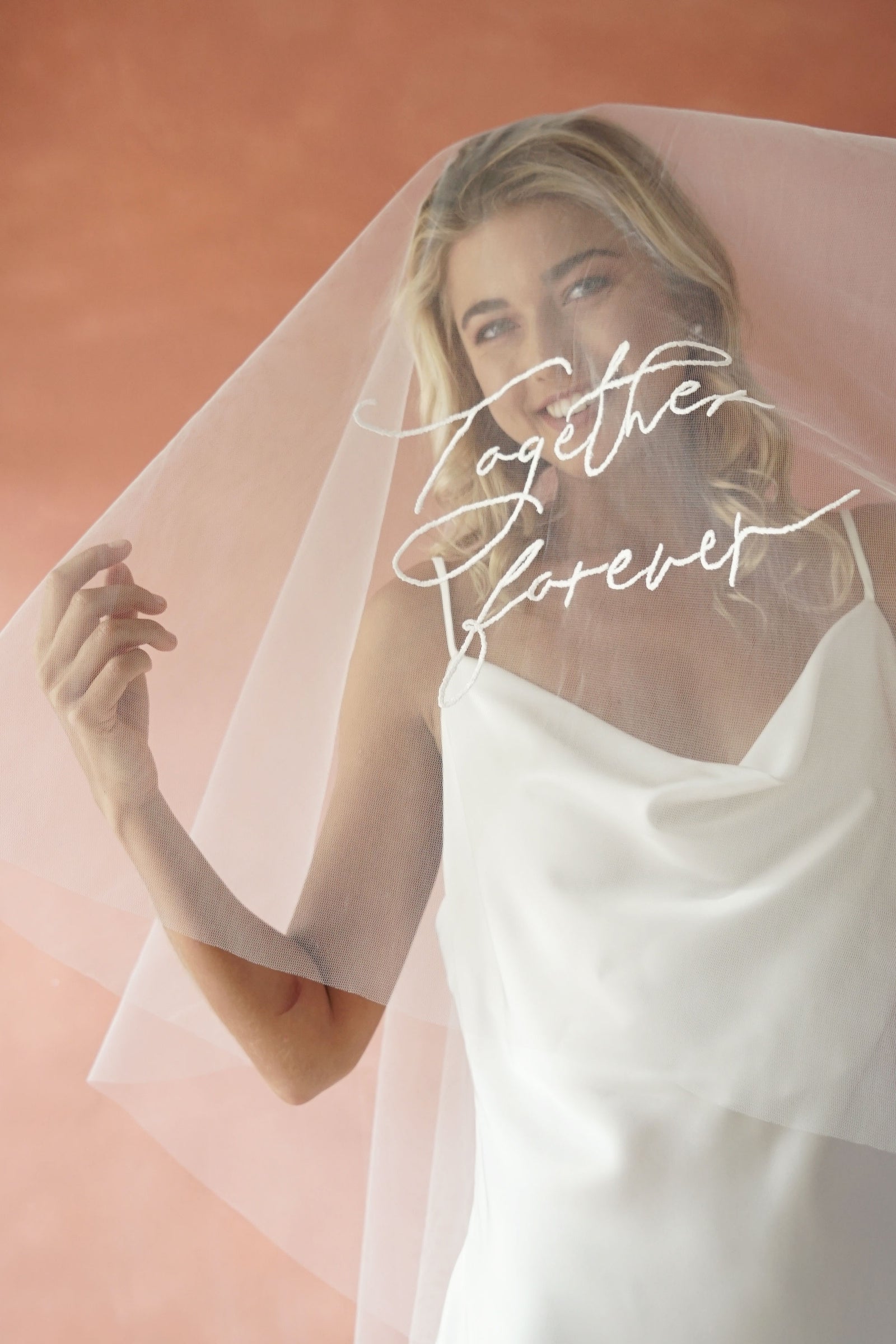 A model wearing a long wedding veil with embroidery text together forever