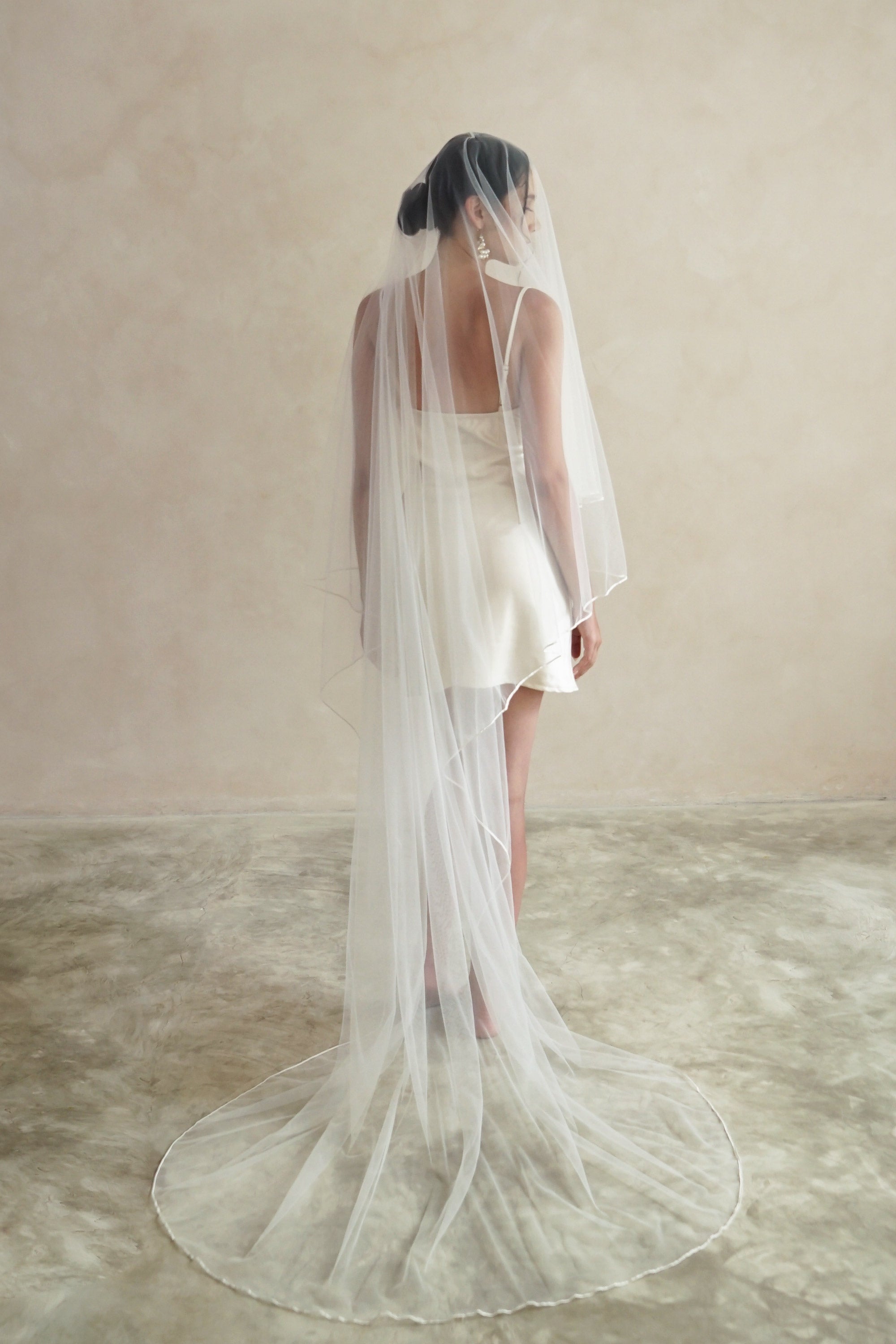 A model wearing a two tier satin cord edge veil